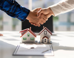 Handshake between real estate agent and international buyer with property contracts and house models in France