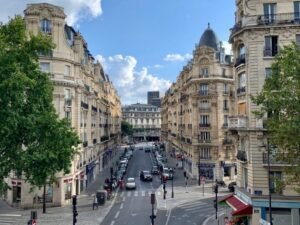 Sun-filled Haussmann apartment interior with French doors and balcony view illustrating Paris property appeal for Australian buyers